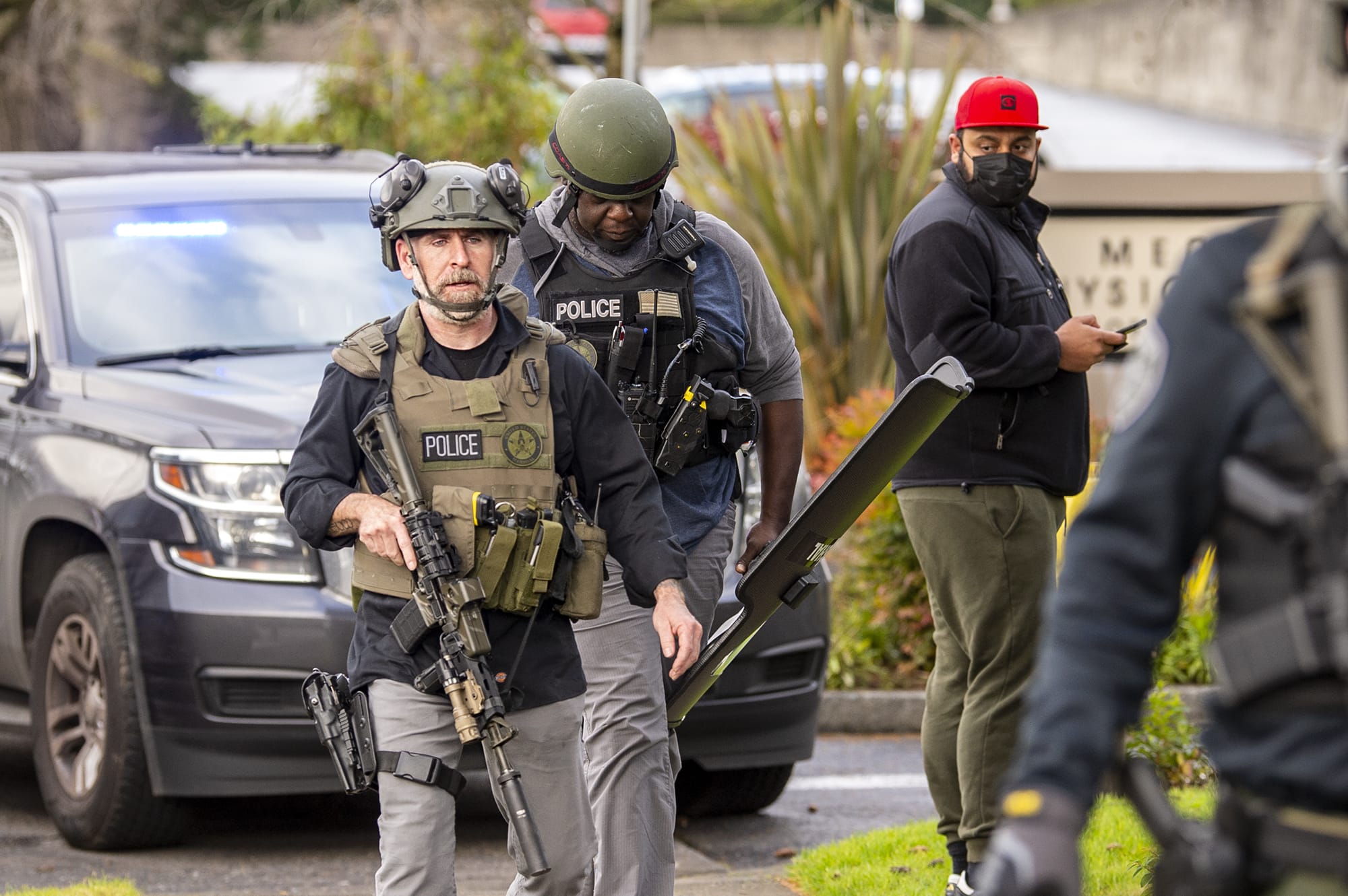 Police officers armed with assault rifles and riot shields exit the building where a shooting reportedly happened on Tuesday, December 22, at the 505 building at the PeaceHealth Southwest Medical Center.