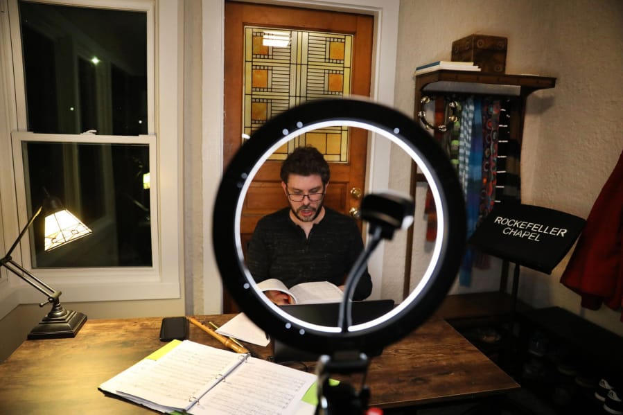 Tenor Matthew Dean sings the &quot;Hallelujah&quot; chorus from Handel&#039;s &quot;Messiah&quot; from inside the back porch of his Oak Park, Ill., home during a Zoom session with members of the Rockefeller Chapel Choir.