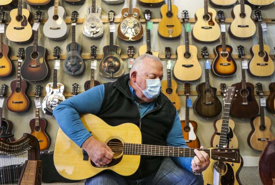 Tom Goetten tests out a guitar by playing it before buying it at Music Folk in Webster Groves on Friday, Nov. 27, 2020. Goetten has been playing guitar for about a year, but has played other instruments throughout his life. (Photo by Cheyenne Boone/St.