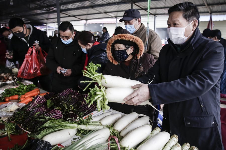 A resident wear masks to buy vegetables in the market on Jan. 23 ,2020 in Wuhan, China.