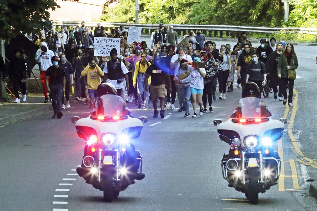 FILE - In this June 1, 2020, file photo, police on motorcycles escort a protest march in Tacoma, Wash., against police brutality and the death of George Floyd. Washington state lawmakers and activists are setting an ambitious agenda for police reform in the upcoming legislative session. They say they hope to make it easier to decertify officers for misconduct, to bar the use of police dogs to make arrests, and to create an independent statewide agency to investigate police killings.(AP Photo/Ted S.