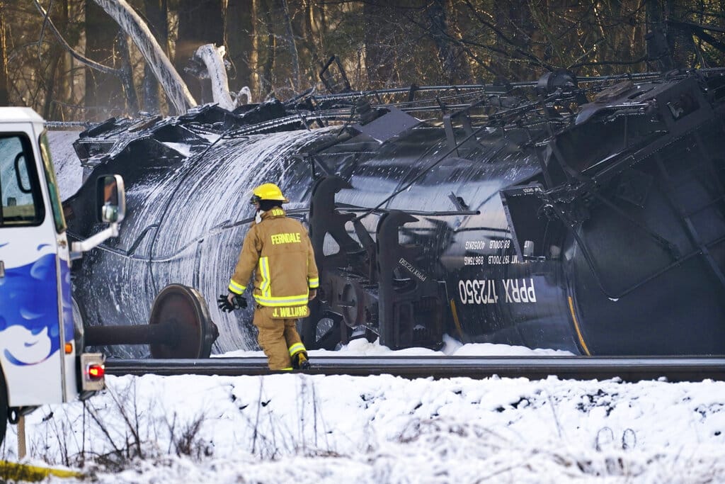 A firefighter walks past a derailed train car Tuesday, Dec. 22, 2020, in Custer, Wash. Officials say seven train cars carrying crude oil derailed and five caught fire north of Seattle and close to the Canadian border. Whatcom County officials said the derailment occurred in the downtown Custer area, where streets were closed and evacuations ordered during a large fire response.