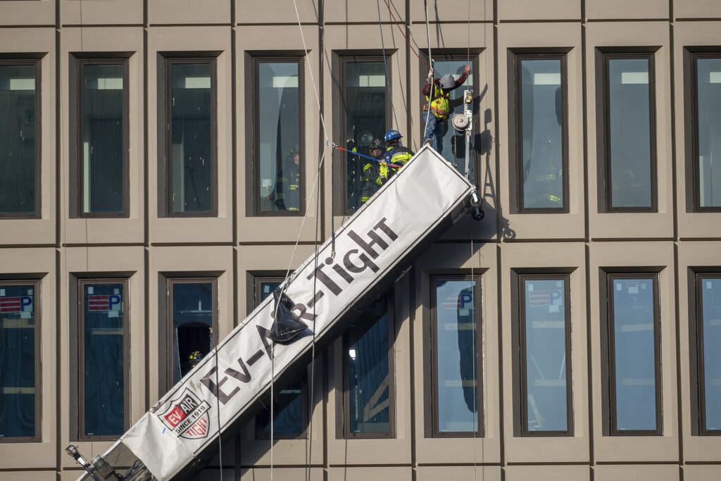 A worker stands on the end of a dangling scaffold as he waits to be rescued following an explosion at Baltimore Gas and Electric's offices, Wednesday, Dec. 23, 2020.  Twenty-one of the victims were brought to area hospitals following the explosion with a partial roof collapse. The city’s fire department tweeted that at least nine of the victims were in critical condition, while another was in serious condition.