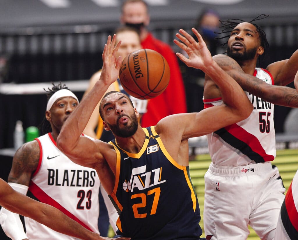 Portland Trail Blazers forward Derrick Jones Jr., right, and Utah Jazz center Rudy Gobert, middle, vie for a rebound as Trail Blazers forward Robert Covington, left, watches during the first half of an NBA basketball game in Portland, Ore., Wednesday, Dec. 23, 2020.