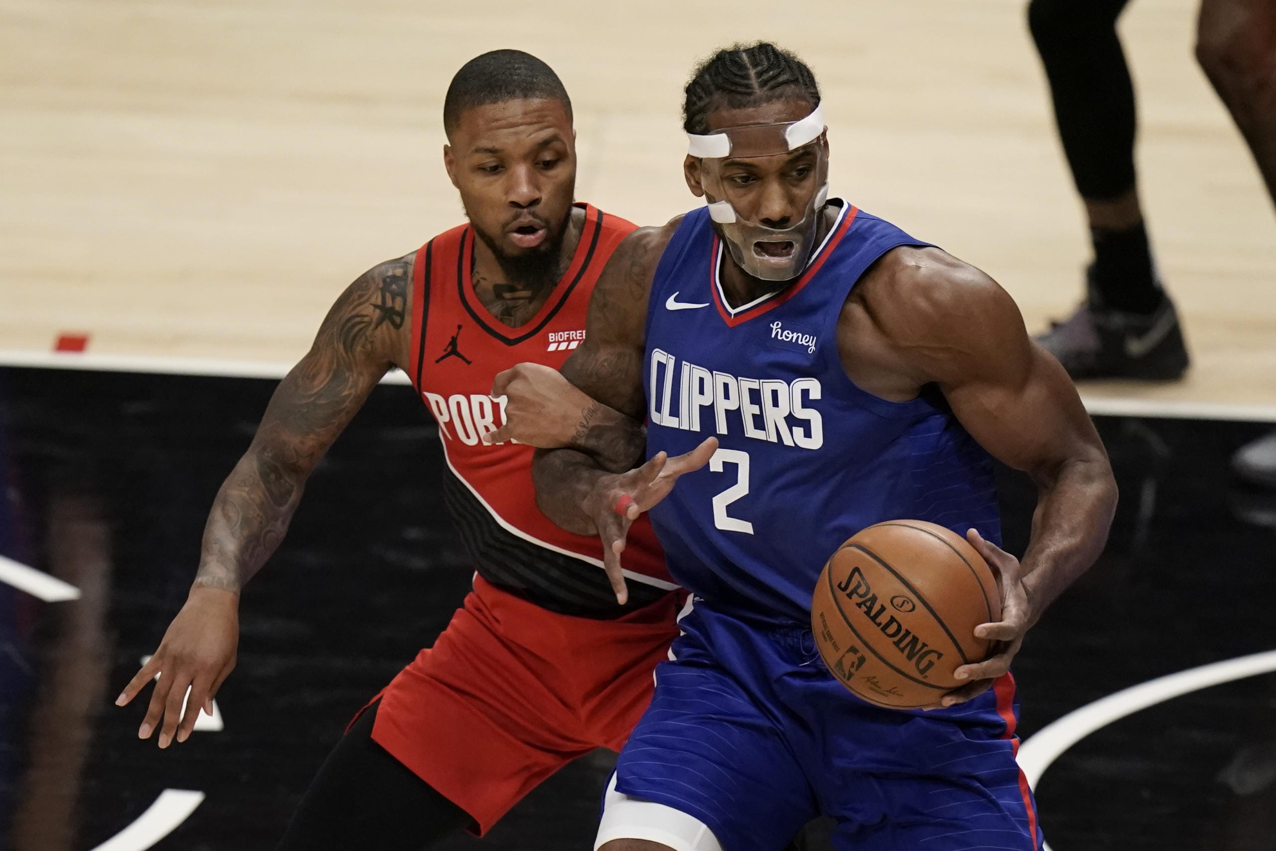 Portland Trail Blazers' Damian Lillard, left, grabs the arm of Los Angeles Clippers' Kawhi Leonard during the first half of an NBA basketball game Wednesday, Dec. 30, 2020, in Los Angeles. (AP Photo/Jae C.