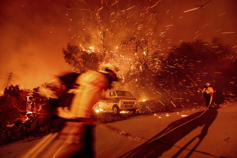 Firefighters battling the Bond Fire haul hose while working to save a home in the Silverado community in Orange County, Calif., on Thursday, Dec. 3, 2020.