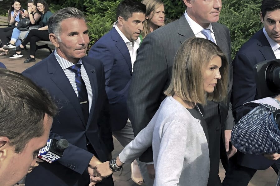 FILE - In this Aug. 27, 2019, file photo, Lori Loughlin departs federal court in Boston with her husband, Mossimo Giannulli, left, after a hearing in a nationwide college admissions bribery scandal.  Giannulli has reported to prison to begin serving his five-month sentence for bribing his daughters&#039; way into college. Giannulli&#039;s wife, &quot;Full House&quot; actor Lori Loughlin, is already behind bars for her role in the college admissions bribery scheme involving prominent parents and elite schools across the country. She began her two-month prison term late last month.