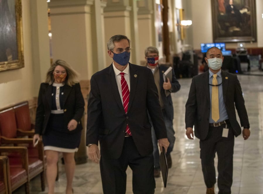Georgia Secretary of State Brad Raffensperger, center, walks with members of his staff as they make their way to a press conference at the Georgia State Capitol building in Atlanta, Wednesday, Dec. 2, 2020.