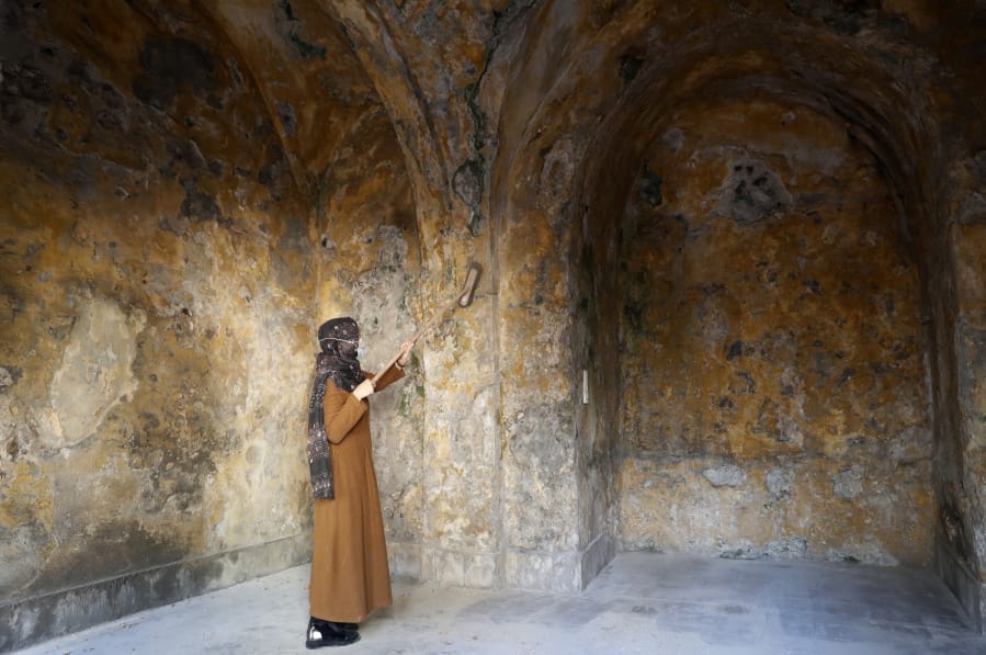 A female artist volunteer cleans a room of the long-abandoned 200-year-old al-Kamalaia school, in the old quarter of Gaza City, Sunday, Dec. 20, 2020. Less than 200 of these old houses are still partly or entirely standing, according to officials and they are threatened by neglect, decaying and urban sprawl.