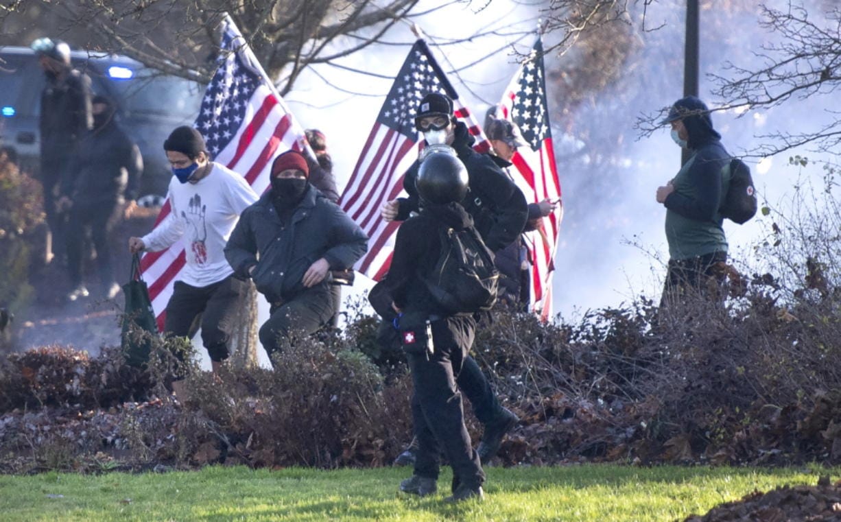 Supporters of President Donald Trump and antifa supporters clashed with Washington state police on the state Capitol Campus in Olympia, Wash., Saturday, Dec. 12, 2020. Police in Olympia declared a riot early Saturday afternoon and arrested at least one person as groups with different points of view held simultaneous protests.