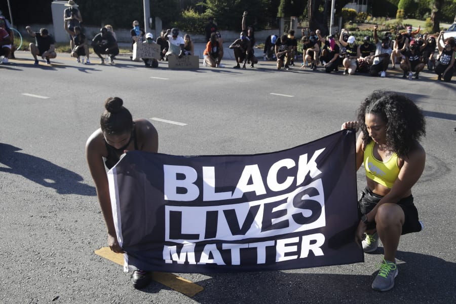 FILE - In this July 11, 2020 file photo, Alycia Pascual-Pena, left, and Marley Ralph kneel while holding a Black Lives Matter banner during a protest in memory of Breonna Taylor, in Los Angeles. Taylor was killed in her apartment by members of the Louisville, Ky., Metro Police Department on March 13. The International Law Enforcement Educators and Trainers Association, a prominent law enforcement training group, is promoting a lengthy research document riddled with falsehoods and conspiracies that urges local police to treat Black Lives Matter activists as terrorists plotting a violent revolution. The document contains misinformation and inflammatory rhetoric that could incite officers against protesters and people of color, critics said.