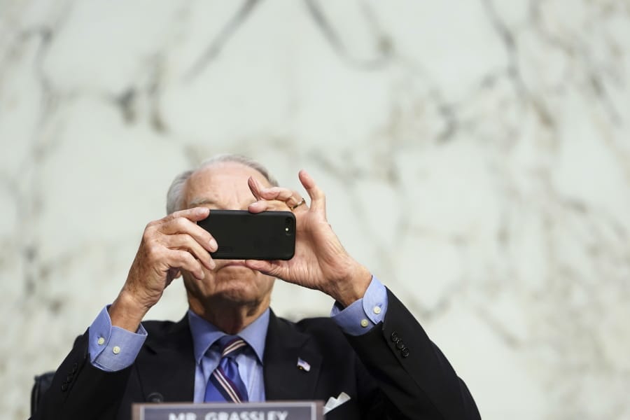 FILE - In this Monday, Oct. 12, 2020 file photo, Sen. Chuck Grassley, R-Iowa, uses his smartphone during a hearing on Capitol Hill in Washington. Researchers from NATO StratCom, a NATO-accredited research group based in Riga, Latvia, paid three Russian companies 300 euros ($368) to buy 337,768 fake likes, views and shares of posts on Facebook, Instagram, Twitter, YouTube and TikTok, including content from verified accounts of Senators Grassley and Chris Murphy. Both senators consented to participate.