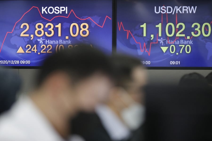 Currency traders watch computer monitors near the screens showing the Korea Composite Stock Price Index (KOSPI), left, and the foreign exchange rate between U.S. dollar and South Korean won at the foreign exchange dealing room in Seoul, South Korea, Monday, Dec. 28, 2020.