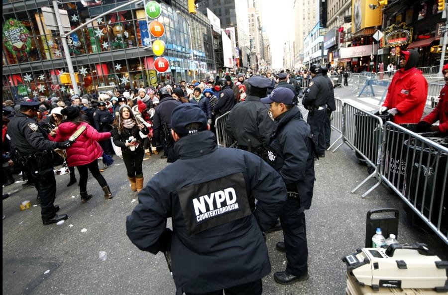 FILE - In this Dec. 31, 2014, file photo, New York Police Department counterterrorism officers, foreground, armed with an explosives detection device, far right, watch as other police officers inspect revelers entering a cordoned off area in Times Square in New York, on New Years Eve. Although New York City police have turned to familiar tactics ahead of the iconic Thursday, Dec. 31, 2020, ball drop, the department&#039;s playbook this year includes an unusual mandate: preventing crowds from gathering in Times Square.
