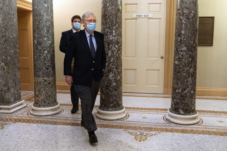 Followed by a staffer, Senate Majority Leader Mitch McConnell of Ky., right, leaves the Capitol for the day, Tuesday, Dec. 29, 2020, on Capitol Hill in Washington.