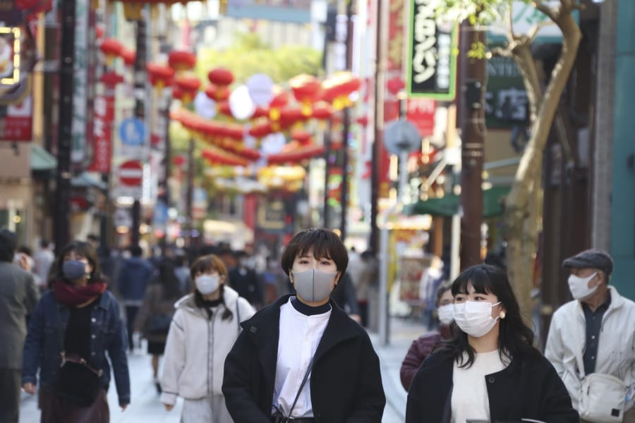People wearing face masks to protect against the spread of the coronavirus walk through China Town in Yokohama, Kanagawa prefecture, near Tokyo, Tuesday, Dec. 1, 2020.