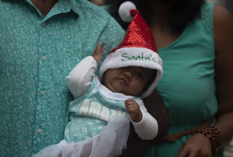 A baby is dressed in a Santa hat at a shopping mall in Johannesburg, South Africa, Tuesday, Dec. 22, 2020.