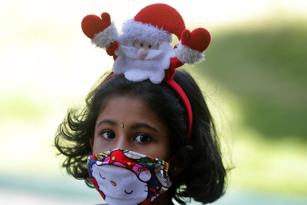 A Sri Lankan Christian girl wears a Santa hair band and a face mask as a precaution against the coronavirus as she arrives at a church to attend the Christmas mass in Colombo, Sri Lanka, Friday, Dec. 25, 2020.