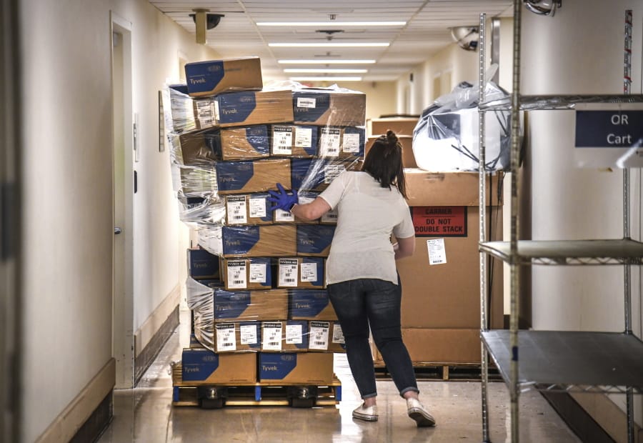 FILE - In this April 4, 2020, file photo, Bethany White, Providence Sacred Heart Medical Center supply chain manager, helps stabilize a shifting pallet of protective gowns as the third of five shipments of PPEs arrived at Sacred Heart from the state in Spokane.