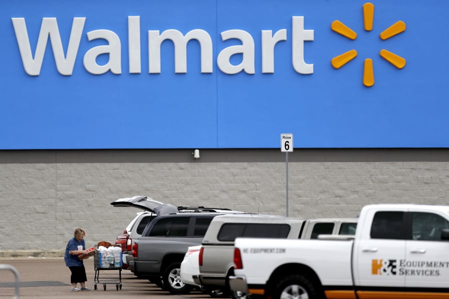 FILE - In this March 31, 2020 file photo, a woman pulls groceries from a cart to her vehicle outside of a Walmart store in Pearl, Miss. Walmart is teaming with the General Motors&#039; Cruise autonomous vehicle unit to test automated package delivery in Arizona.