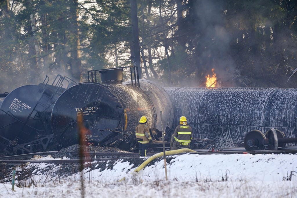 Firefighters look on as deraileded train cars continue to burn Tuesday, Dec. 22, 2020, in Custer, Wash. Officials say seven train cars carrying crude oil derailed and five caught fire north of Seattle and close to the Canadian border. Whatcom County officials said the derailment occurred in the downtown Custer area, where streets were closed and evacuations ordered during a large fire response.