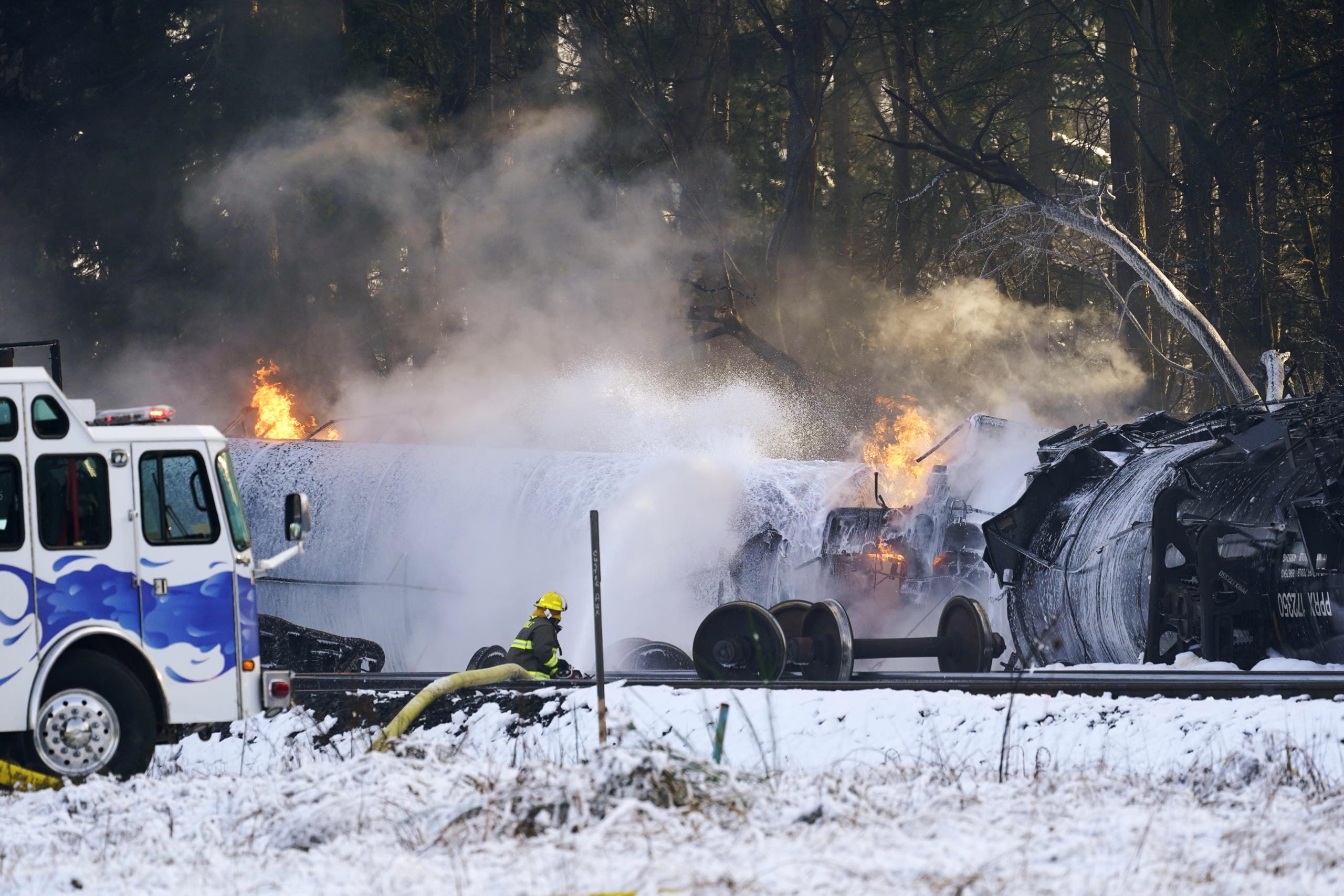 A firefighter sprays foam on burning, derailed train cars Tuesday, Dec. 22, 2020, in Custer, Wash. Officials say seven train cars carrying crude oil derailed and five caught fire north of Seattle and close to the Canadian border. Whatcom County officials said the derailment occurred in the downtown Custer area, where streets were closed and evacuations ordered during a large fire response.