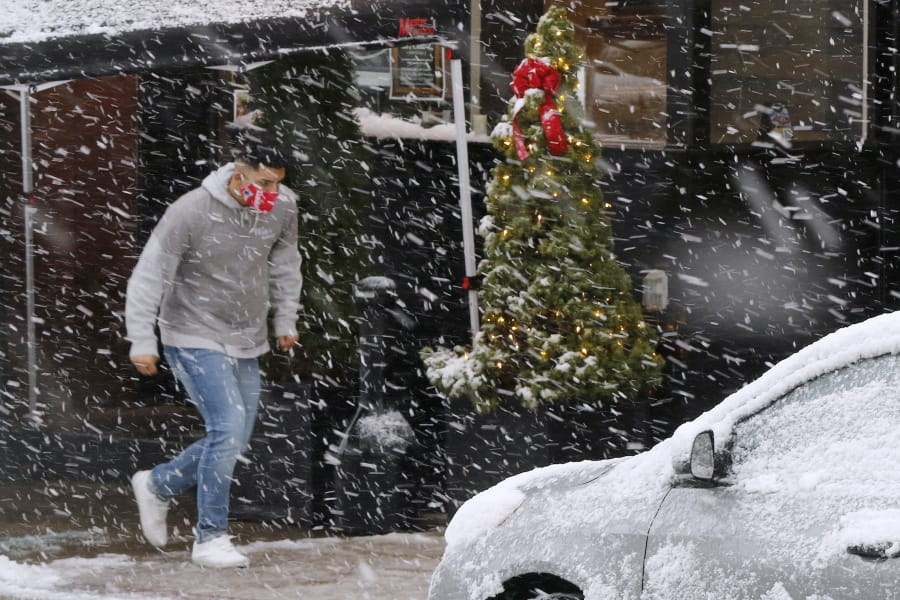 A man runs through heavy snow, Saturday, Dec. 5, 2020, downtown in Marlborough, Mass. The northeastern United States is seeing the first big snowstorm of the season.