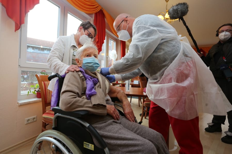 Doctor Bernhard Ellendt, right, injects the COVID-19 vaccine to nursing home resident Edith Kwoizalla, 101 years old, in Halberstadt, Germany, Saturday, Dec. 26, 2020. The first shipments of coronavirus vaccines have arrived across the European Union as authorities prepared to begin administering the first shots to the most vulnerable people in a coordinated effort on Sunday. The vaccines developed by BioNTech and Pfizer arrived by truck in warehouses across the continent on Friday and early Saturday after being sent from a manufacturing center in Belgium before Christmas.
