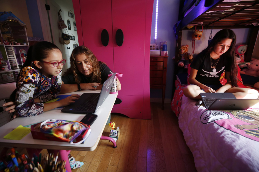 LOS ANGELES, CA - SEPTEMBER 17: 9-year-old Priscilla Guerrero uses a laptop computer for her 4th grade Los Angeles Unified School District online class in her room as mom Sofia Quezada assists her and 13-year-old sister Paulette Guerrero during remote learning lessons at home on September 17, 2020. Boyle Heights on Thursday, Sept. 17, 2020 in Los Angeles, CA.