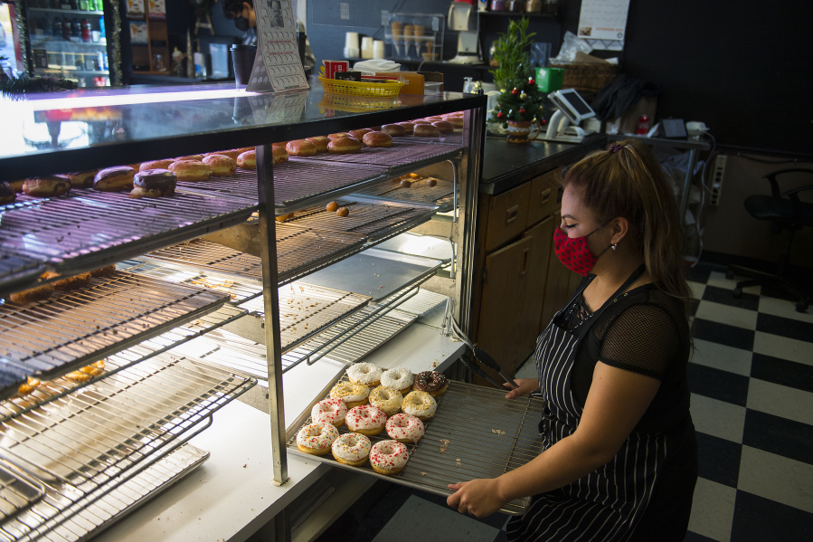 Jessica Sanchez, co-owner of Tonallis Doughnuts &amp; Cream, looks over a selection of fresh doughnuts. Business has been slow for Tonallis during the pandemic, but Sanchez said she has faith that it will pick up.