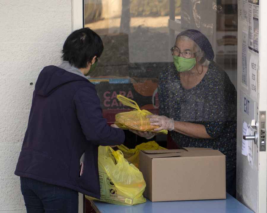 Volunteer Libby Bryant helps a food recipient at FISH Westside Food Pantry of Vancouver. The pantry serves about 1,200 families, or 3,500 people every month, Executive Director James Fitzgerald said.