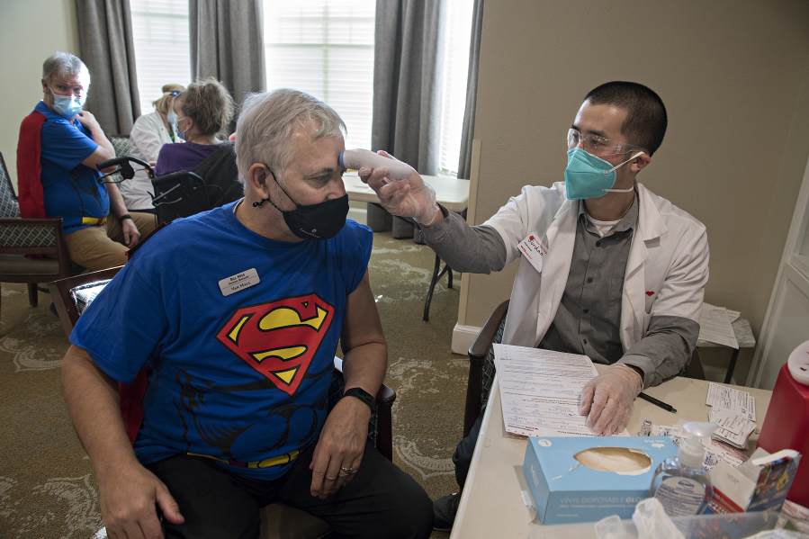 Van Mall Retirement General Manager Bill Hess, left, harnesses his superpowers while getting his COVID-19 vaccination from Jordan Tran of CVS Pharmacy on Friday at Van Mall Retirement. Hess was among the 205 staff and residents that were vaccinated last week. Van Mall had a superhero theme to celebrate staff and residents.
