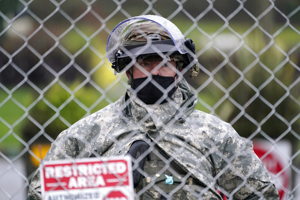 A member of the Washington National Guard stands at a fence surrounding the Capitol in anticipation of protests Monday, Jan. 11, 2021, in Olympia, Wash. State capitols across the country are under heightened security after the siege of the U.S. Capitol last week. (AP Photo/Ted S.