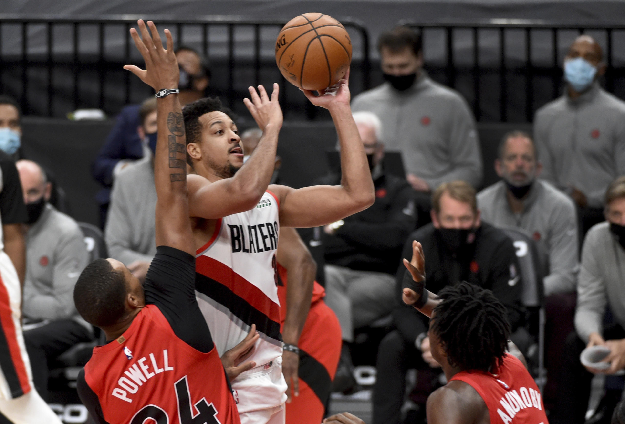 Portland Trail Blazers guard CJ McCollum, center, drives to the basket on Toronto Raptors guard Norman Powell, left, and forward OG Anunoby, right, during the second half of an NBA basketball game in Portland, Ore., Monday, Jan. 11, 2021. The Blazers won 112-111.