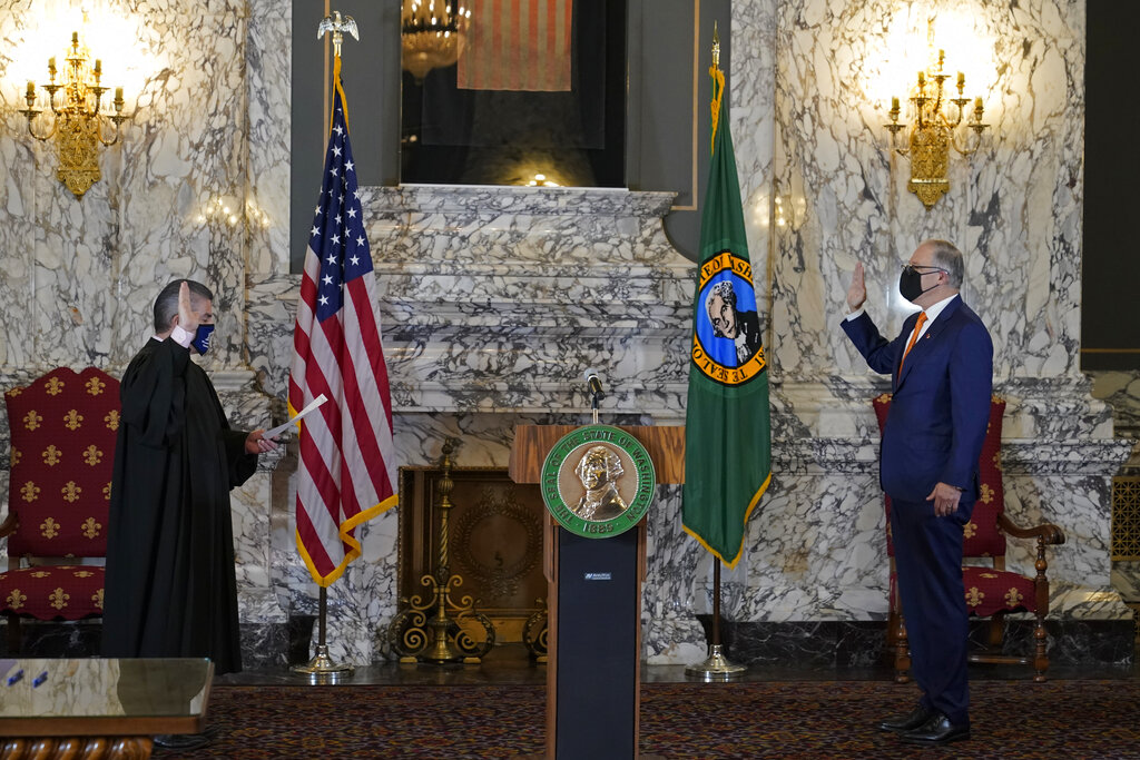 Washington Gov. Jay Inslee, right, takes the oath of office for his third term as Governor, as administered by Washington Supreme Court Chief Justice Steven Gonzalez, left, Wednesday, Jan. 13, 2021, during a ceremony at the Capitol in Olympia, Wash. (AP Photo/Ted S.