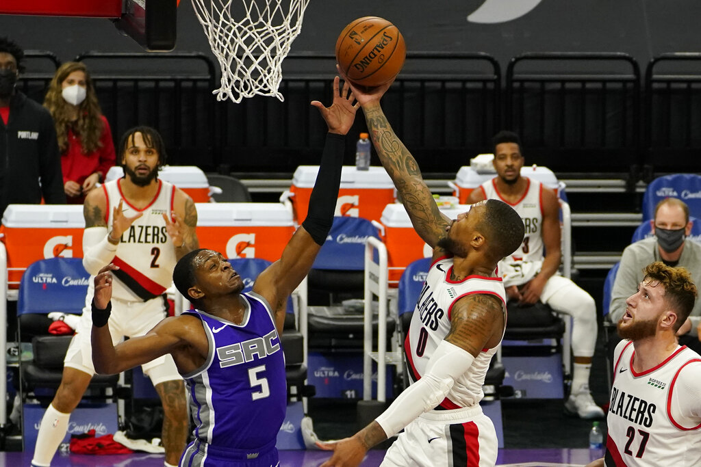 Portland Trail Blazers guard Damian Lillard, right, goes to the basket against Sacramento Kings guard De'Aaron Fox, left, during the first quarter of an NBA basketball game in Sacramento, Calif., Wednesday, Jan. 13, 2021.