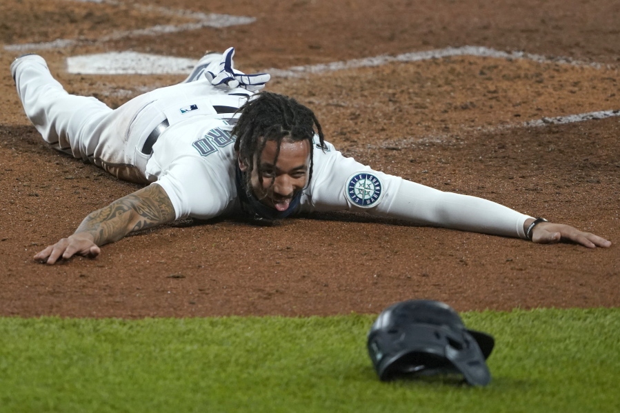 Seattle Mariners shortstop J.P. Crawford sprawls on the dirt and reacts after sliding safely home during the fifth inning of a baseball game against the Houston Astros, Wednesday, Sept. 23, 2020, in Seattle. Crawford scored on a double hit by Kyle Seager. (AP Photo/Ted S.