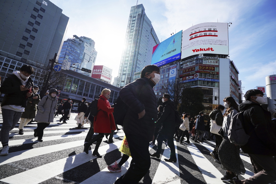People wearing protective masks to help curb the spread of the coronavirus walk along pedestrian crossings Monday, Jan. 25, 2021 in Tokyo. The Japanese capital confirmed more than 600 new coronavirus cases on Monday.