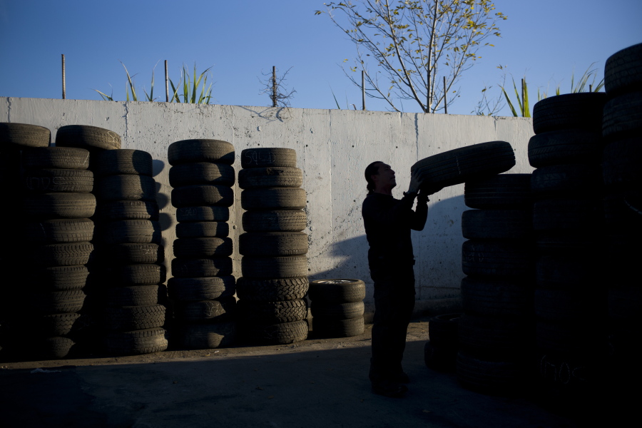 FILE- In this Thursday, Nov. 19, 2015, file photo, junkyard employee Fabio Flores stacks up used tires at Aadlen Brothers Auto Wrecking, also known as U Pick Parts, in the Sun Valley section of Los Angeles. California may ask tire manufacturers to look at ways of eliminating zinc from their products because studies have shown the mineral may harm aquatic wildlife when it is washed into rivers and lakes. (AP Photo/Jae C.
