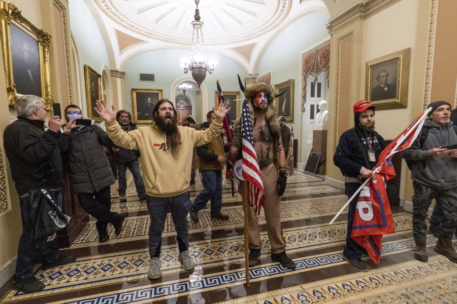 FILE - In this Wednesday, Jan. 6, 2021 file photo supporters of President Donald Trump are confronted by U.S. Capitol Police officers outside the Senate Chamber inside the Capitol in Washington. Jacob Anthony Chansley, the Arizona man with the painted face and wearing a horned, fur hat, was taken into custody Saturday, Jan. 9, 2021 and charged with counts that include violent entry and disorderly conduct on Capitol grounds.