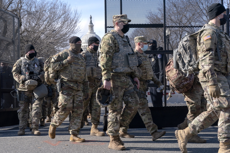 With the U.S. Capitol in the background, members of the National Guard change shifts as they exit through anti-scaling security fencing on Saturday, Jan. 16, 2021, in Washington as security is increased ahead of the inauguration of President-elect Joe Biden and Vice President-elect Kamala Harris.
