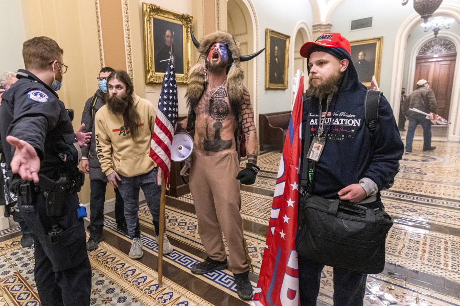 FILE - In this Wednesday, Jan. 6, 2021 file photo, supporters of President Donald Trump, including Jacob Chansley, center with fur hat, are confronted by Capitol Police officers outside the Senate Chamber inside the Capitol in Washington.