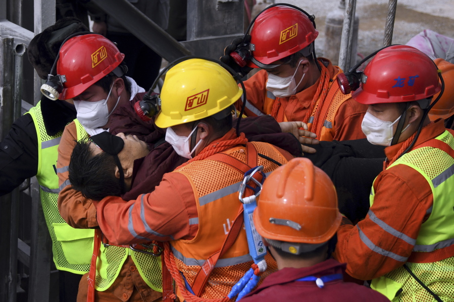 In this photo released by Xinhua News Agency, rescuers carry a miner who was trapped in a mine to an ambulance in Qixia City in east China&#039;s Shandong Province, Sunday, Jan. 24, 2021. Eleven workers trapped for two weeks by an explosion inside a Chinese gold mine were brought safely to the surface on Sunday.