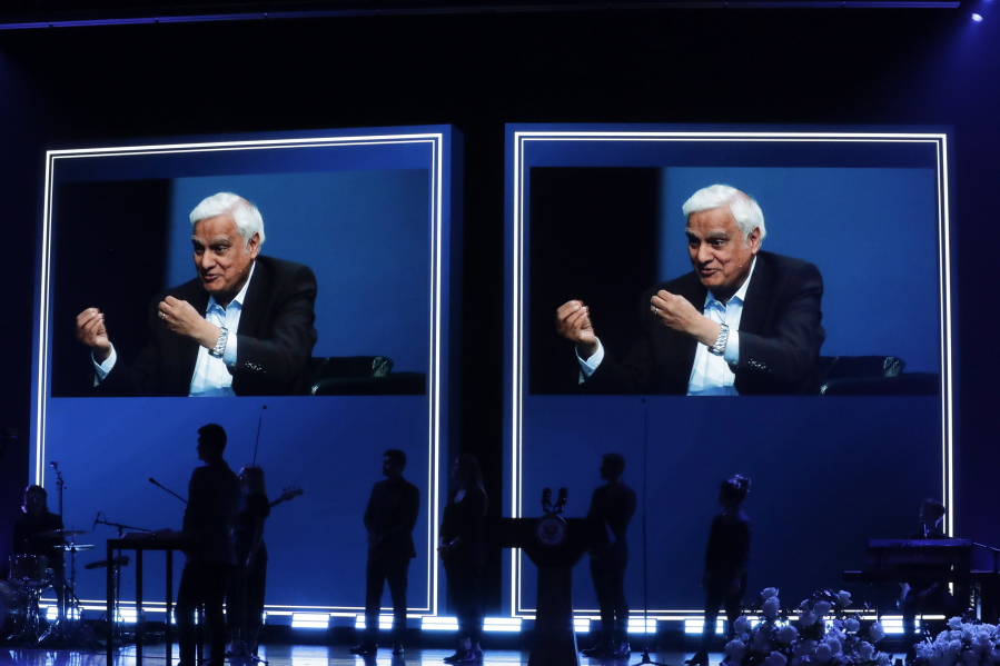 FILE - In this May 29, 2020 file photo, images of Ravi Zacharias are displayed in the Passion City Church during a memorial service for him in Atlanta. A posthumous sex scandal involving  Zacharias, who founded the Ravi Zacharias International Ministries has placed the global organization in a wrenching predicament.