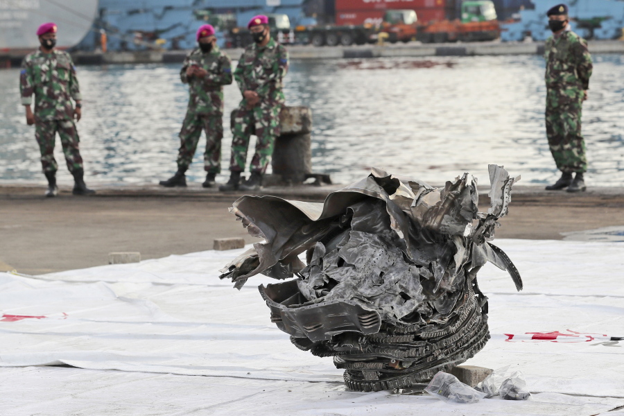 Indonesian marines look at a large part of a plane recovered from the waters off Java Island where Sriwijaya Air flight SJ-182 crashed on Saturday, at Tanjung Priok Port in Jakarta, Indonesia, Monday, Jan. 11, 2021. The search for the black boxes of the crashed Sriwijaya Air jet intensified Monday to boost the investigation into what caused the plane carrying 62 people to nosedive at high velocity into the Java Sea.