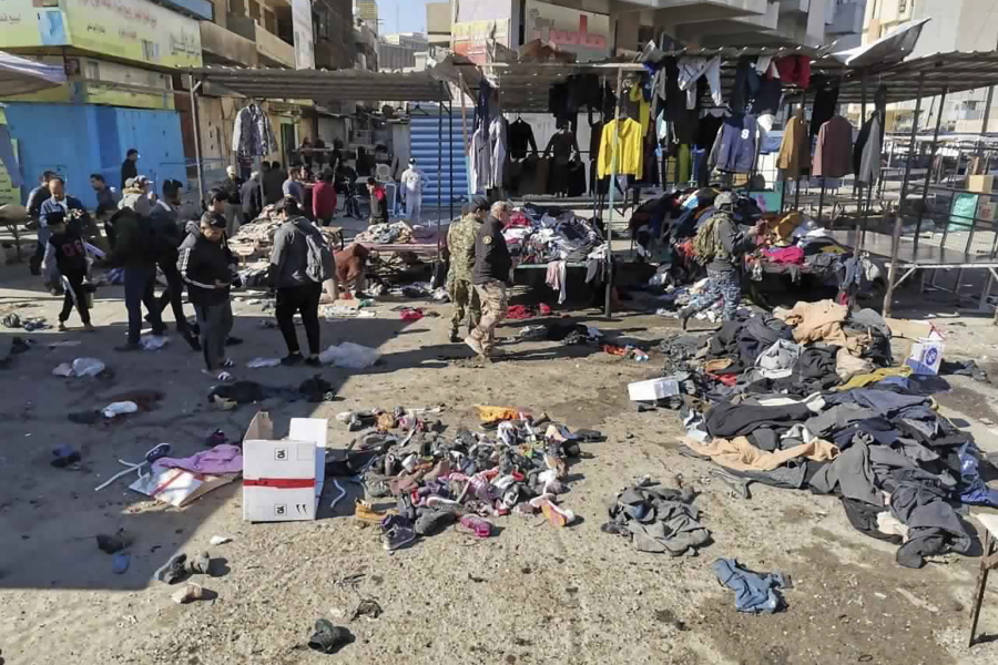 FILE - In this Thursday, Jan. 21, 2021, file photo, people and security forces gather at the site of a deadly bomb attack in a market selling used clothes, in Baghdad, Iraq. The Islamic State group has claimed responsibility for a rare suicide attack that rocked central Baghdad, killing 32 people and wounding dozens.