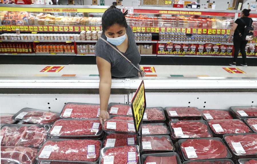 FILE - In this April 29, 2020 file photo, amid concerns of the spread of COVID-19, a shopper wears a mask as she looks over meat products at a grocery store in Dallas.  U.S. wholesale prices rose 0.3% in December led by a the biggest jump in energy costs since June. The Labor Department reported Friday, Jan.
