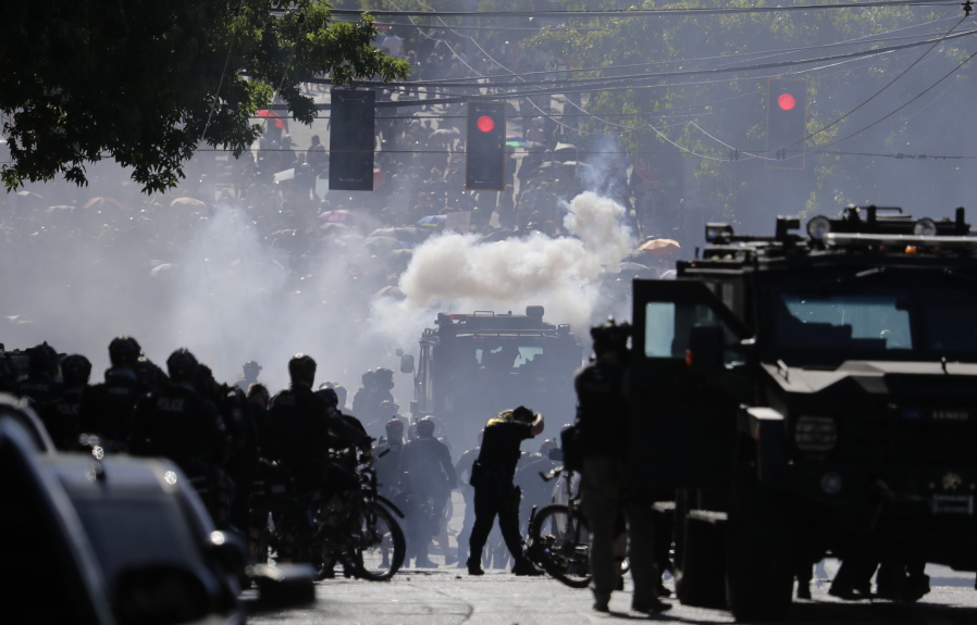 FILE - In this July 25, 2020, file photo, smoke rises as police clash with protester during a Black Lives Matter protest near the Seattle Police East Precinct headquarters in Seattle. A Seattle police officer who threw a tear gas canister that hit a reporter and other officers who threw blast balls that hit individuals during last summer&#039;s Black Lives Matter protests violated policies, according to new reports from an independent agency tasked with investigating police misconduct. The agency has released five batches of investigative reports since September, with the latest 22 cases posted Friday, Jan. 15, 2021. (AP Photo/Ted S.