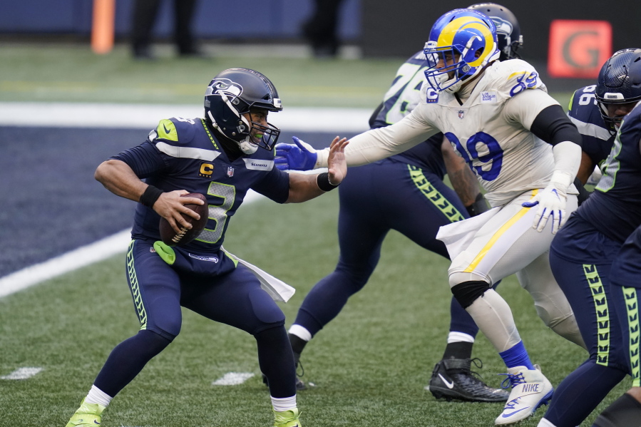Seattle Seahawks quarterback Russell Wilson (3) tries to fend off a sack by Los Angeles Rams defensive lineman Aaron Donald (99) during the second half of an NFL football game, Sunday, Dec. 27, 2020, in Seattle.