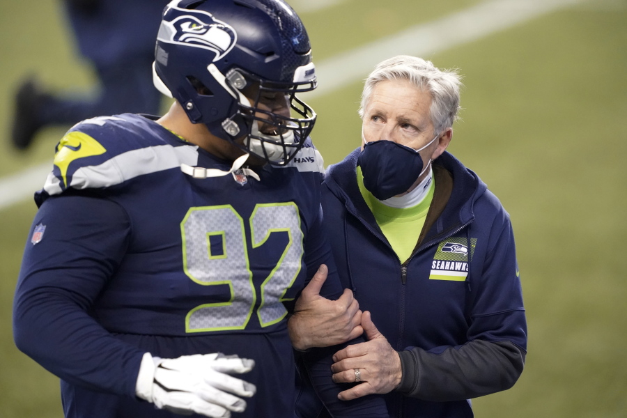 Seattle Seahawks head coach Pete Carroll, right, walks off the field with defensive tackle Bryan Mone after the team lost to the Los Angeles Rams in an NFL wild-card playoff football game, Saturday in Seattle. (Ted S.